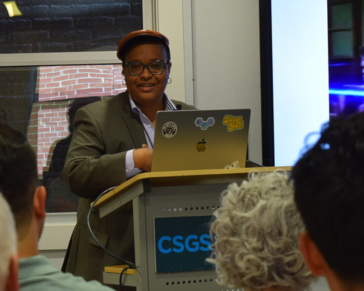 People seated listening to a speaker and looking at a presentation.
