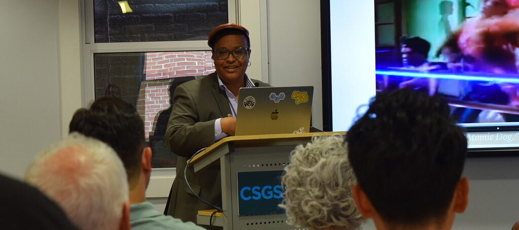 People seated listening to a speaker and looking at a presentation.